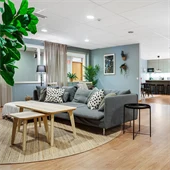 Vardagsrum med grå soffa och runt matbord mot mintgrön vägg