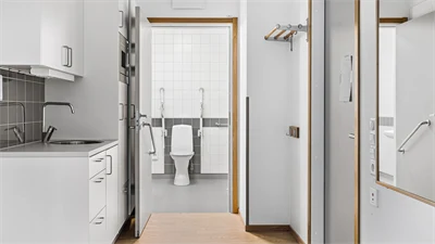 Toalett, vita väggar och brunt golv