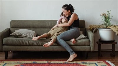 Vuxen som kramar om barn i en soffa