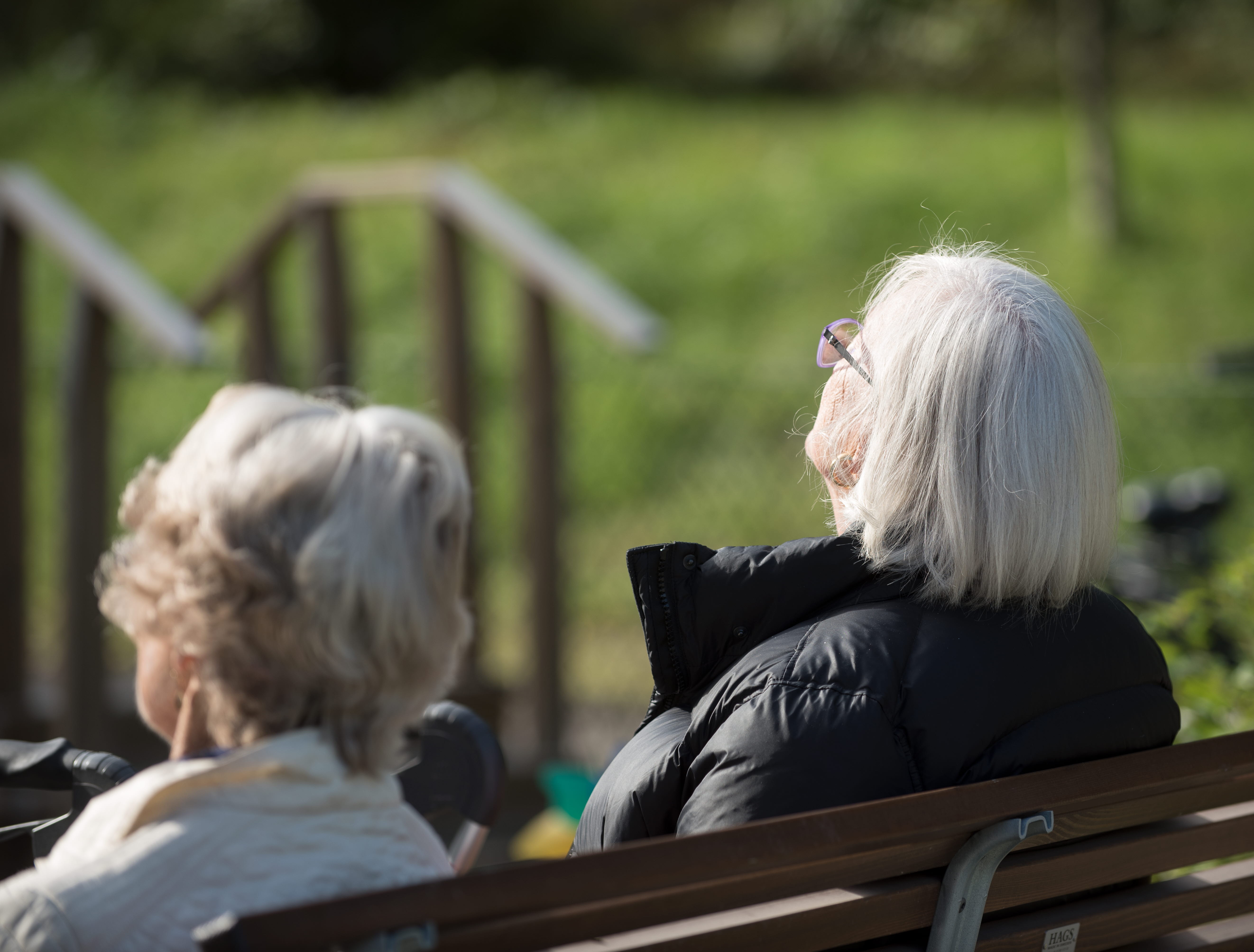 A group of people sitting on a bench in the sun