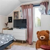 A large brown teddy bear sitting on top of a bed
