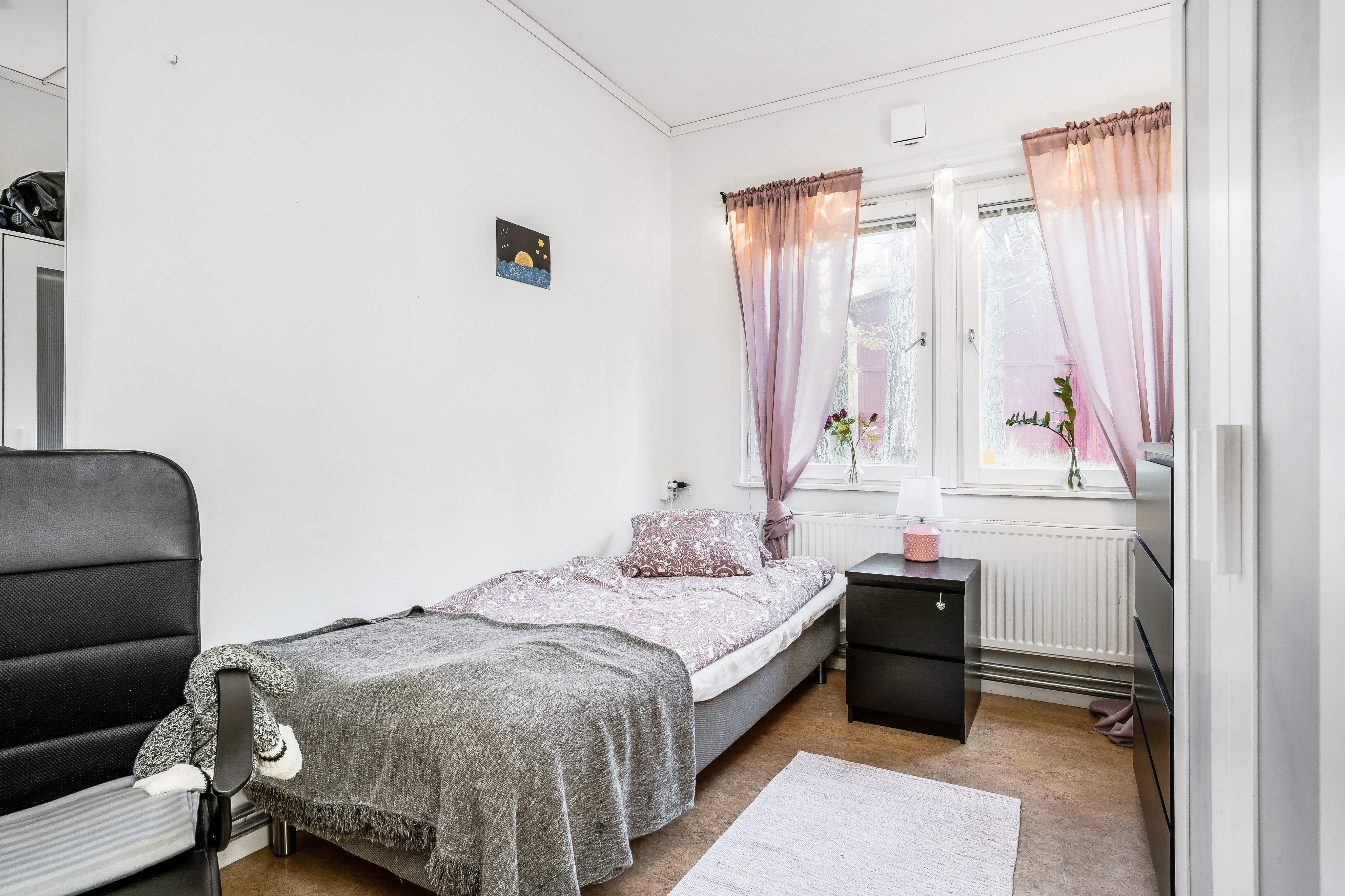 A bedroom with a bed and a chair in a room