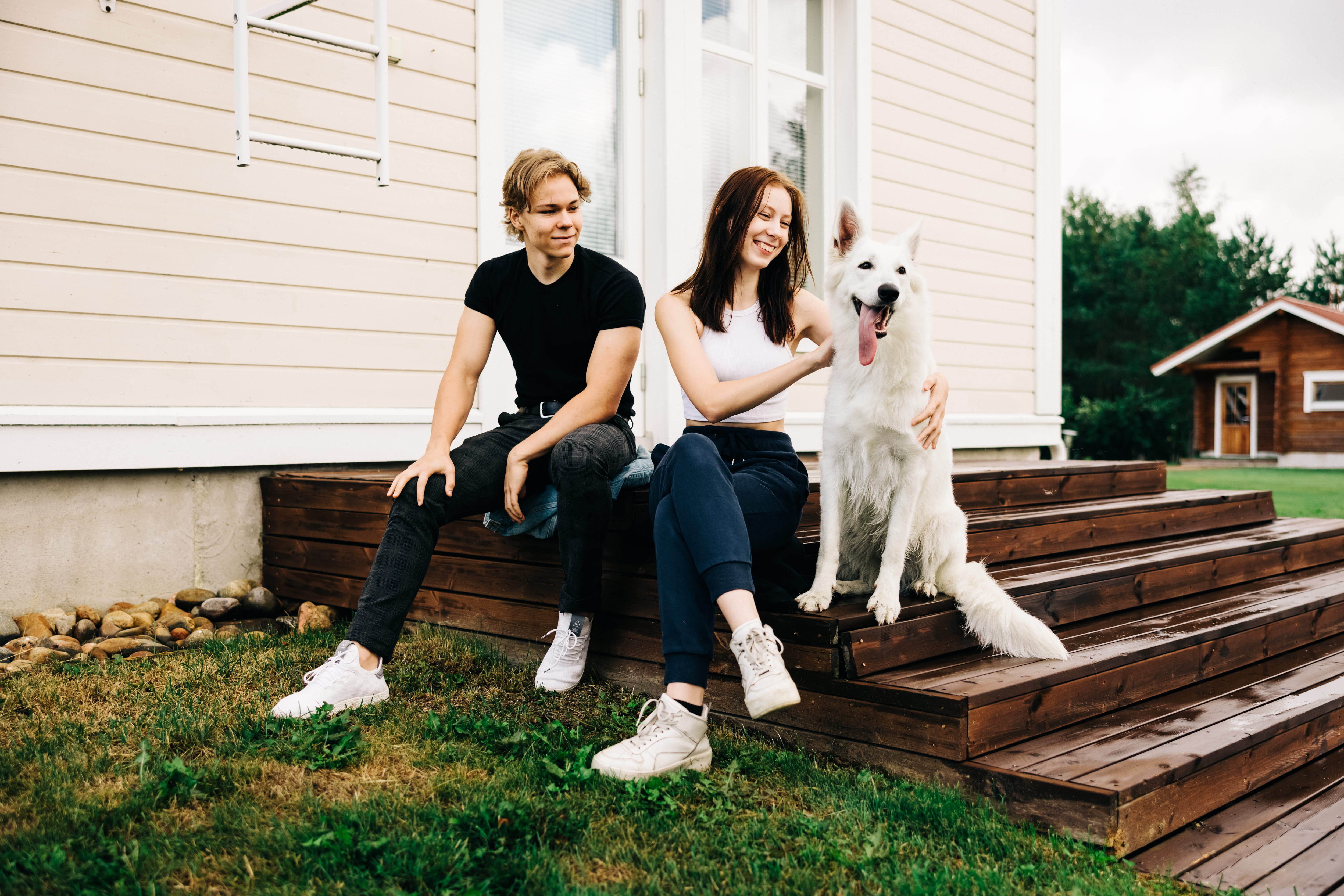 Two young people and a dog are sitting on the stairs.