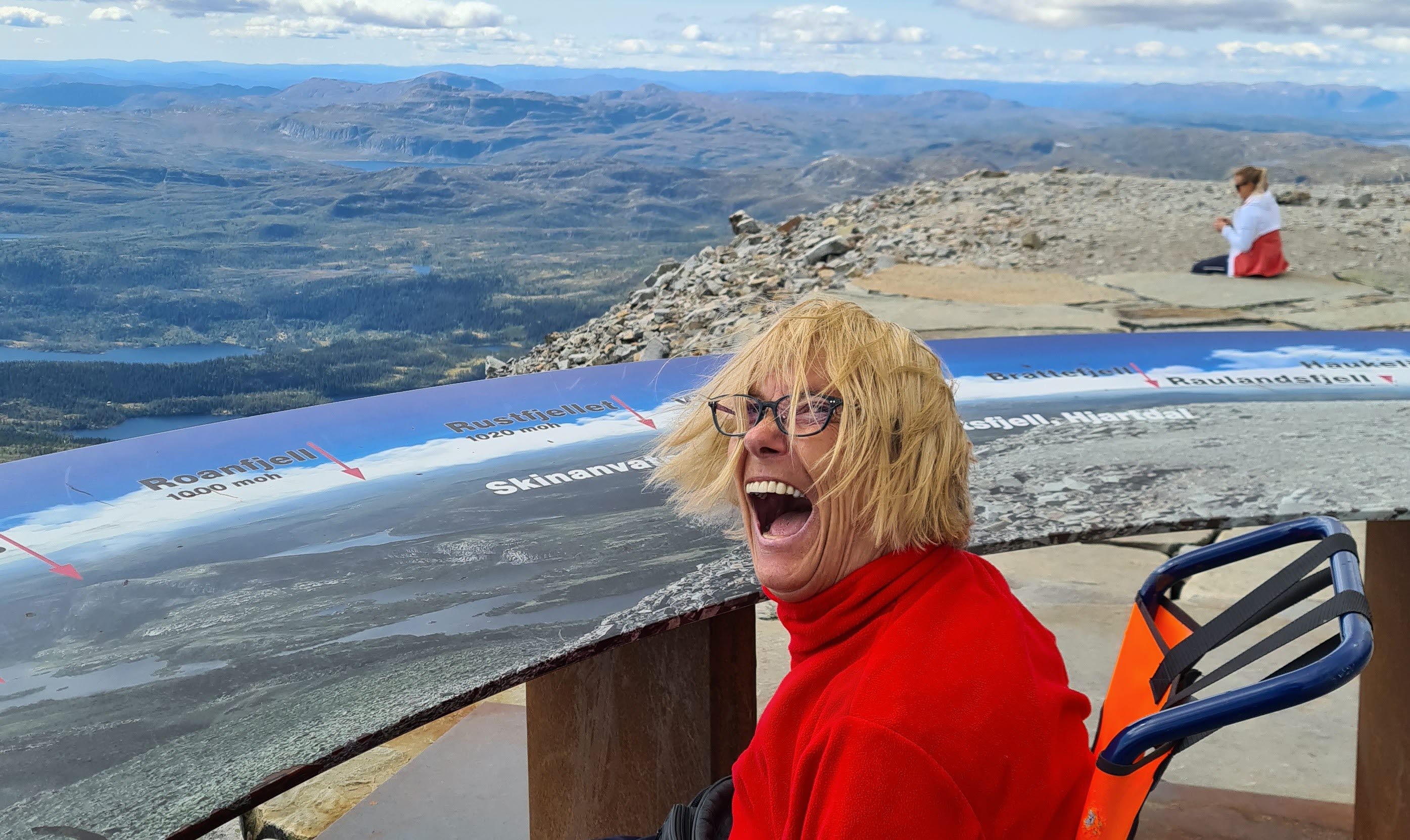 Smalt bilde - Inger smiler i rullestol på toppen av Gaustatoppen