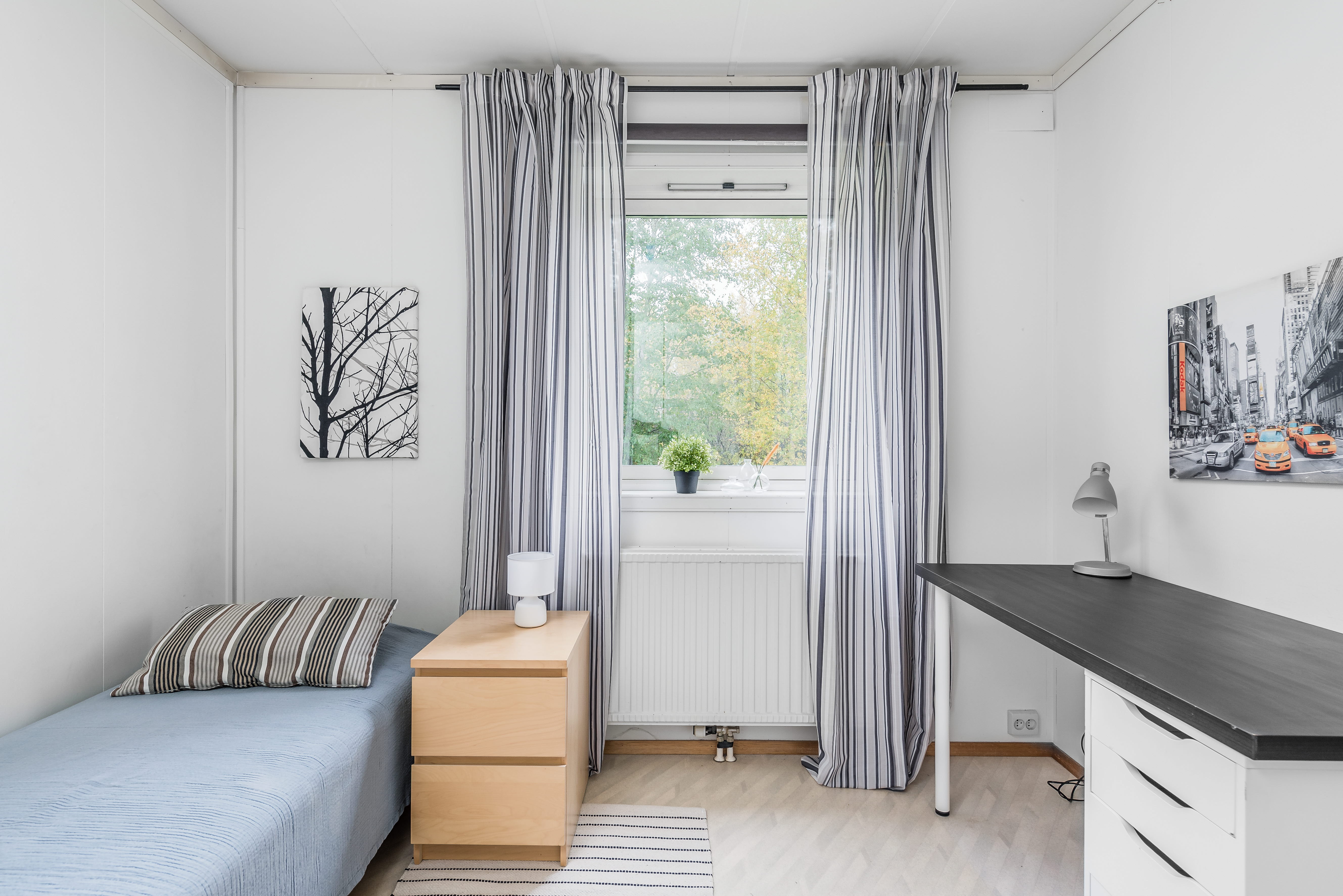 A bedroom with a bed and desk in a room