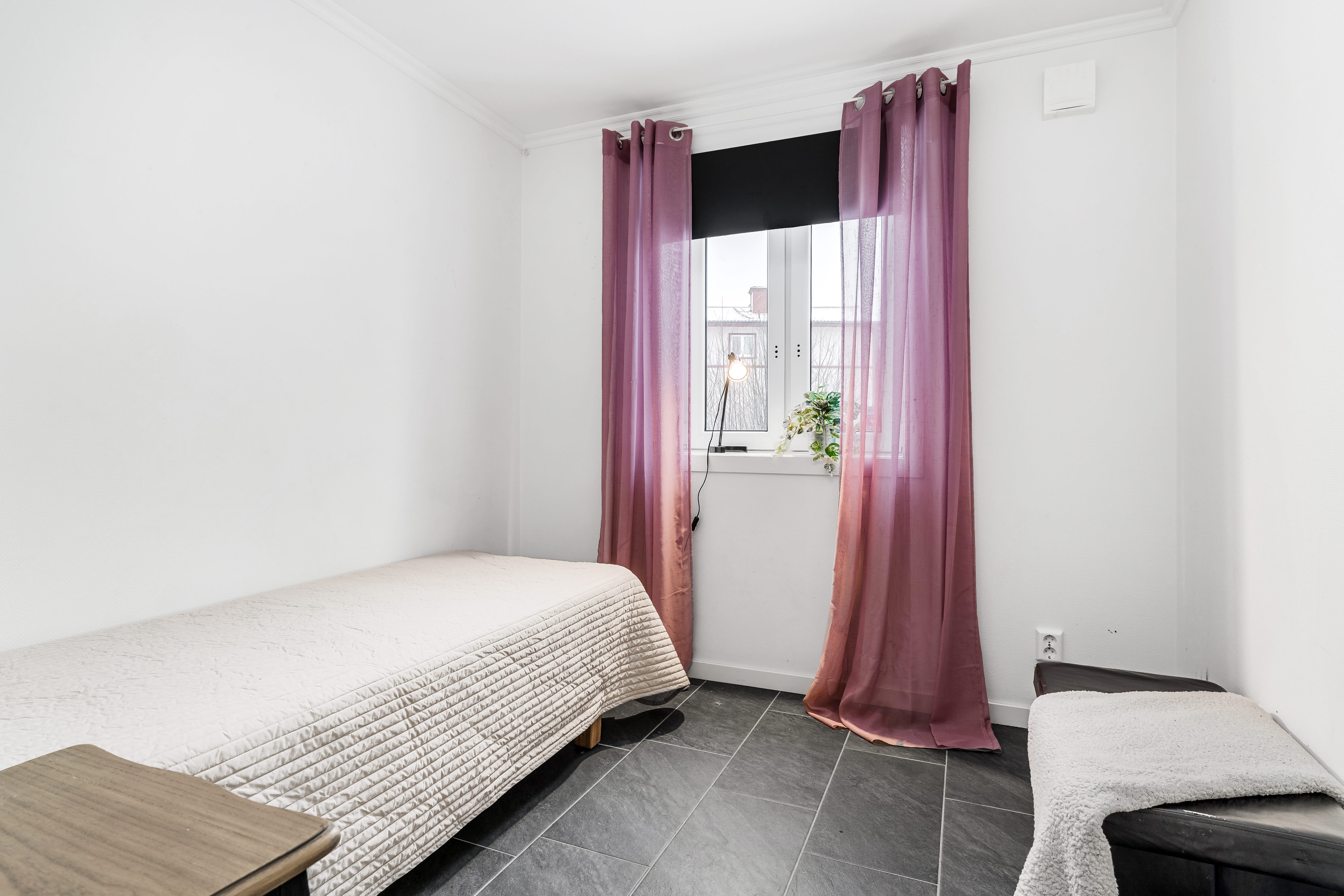 A bedroom with a bed and desk in a small room