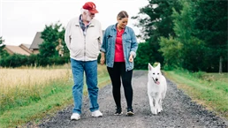 Two people and a dog go for a walk.