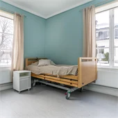 Sovrum med två fönster och en säng. Väggarna är blå. 