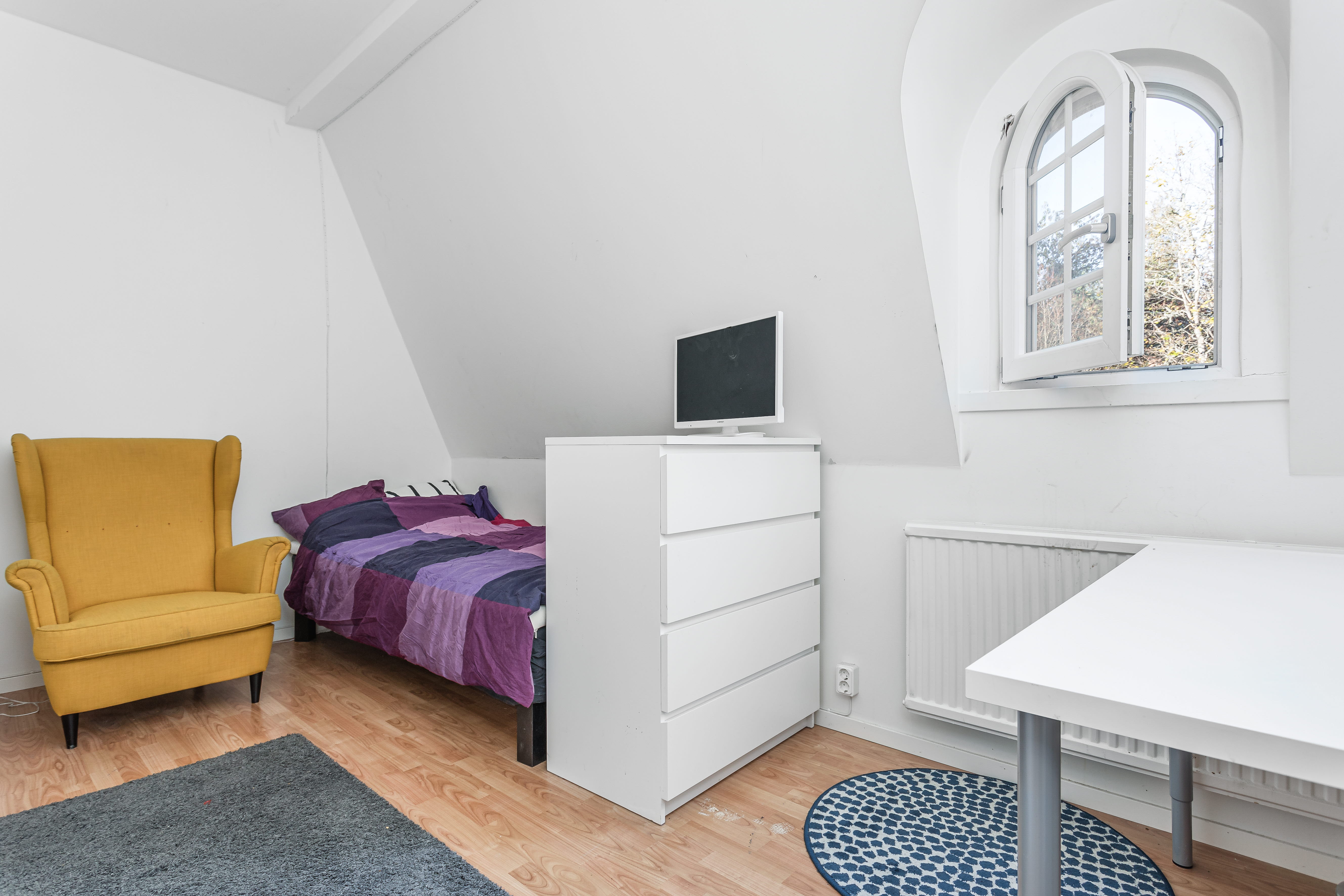 A bedroom with a bed and desk in a room