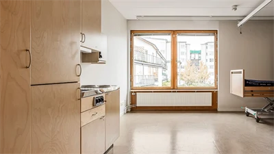Kök med stort fönster, vita väggar och brunt golv