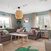 Vardagsrum med brun soffa och färgglada kuddar. 