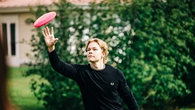 Nuori mies heittää frisbeetä.