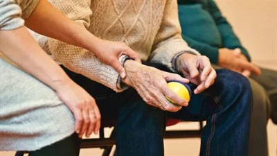 Elderly man holds a small ball