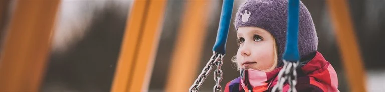 A girl is standing under a swing.