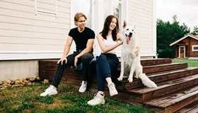 Two young people and a dog are sitting on the stairs.