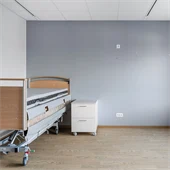 Sovrum med säng,  grå vägg och brunt golv