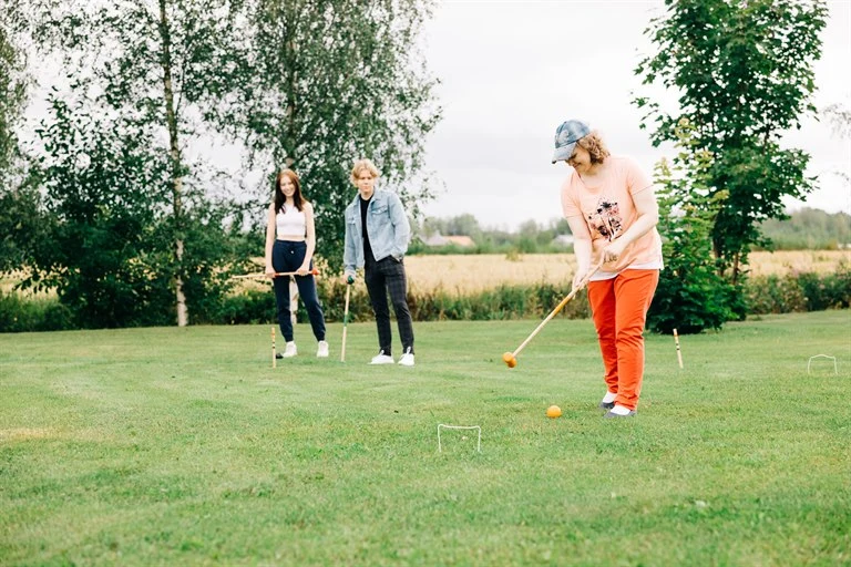 A group of young people playing croquet.
