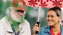Kvinna håller paraply över äldre man