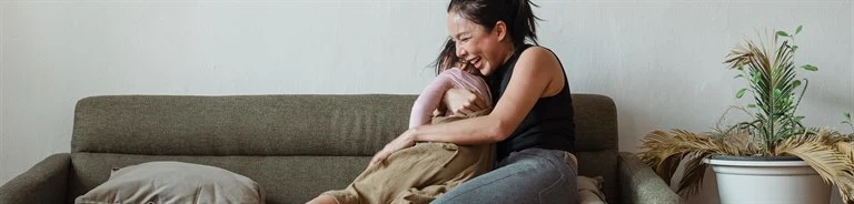 Vuxen som kramar om barn i en soffa