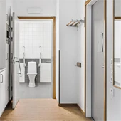 Toalett, vita väggar och brunt golv