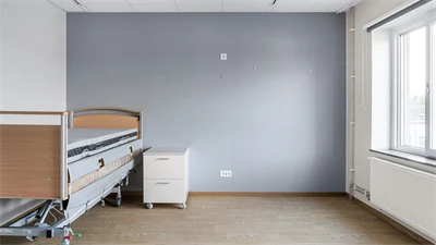 Sovrum med säng,  grå vägg och brunt golv