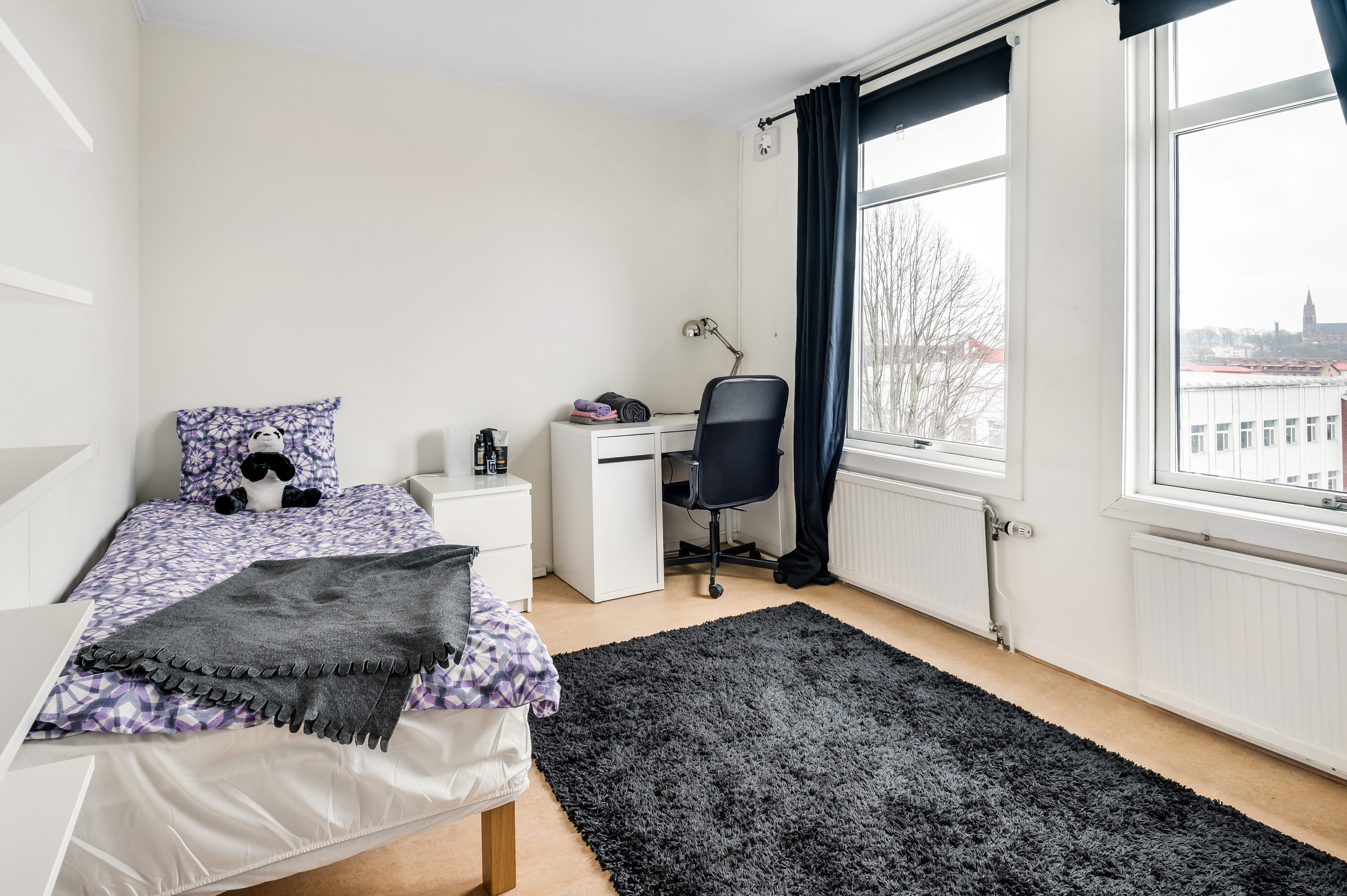 A bedroom with a bed and window in a room