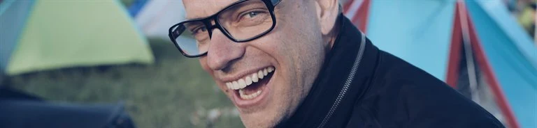 A man wearing glasses and smiling at the camera