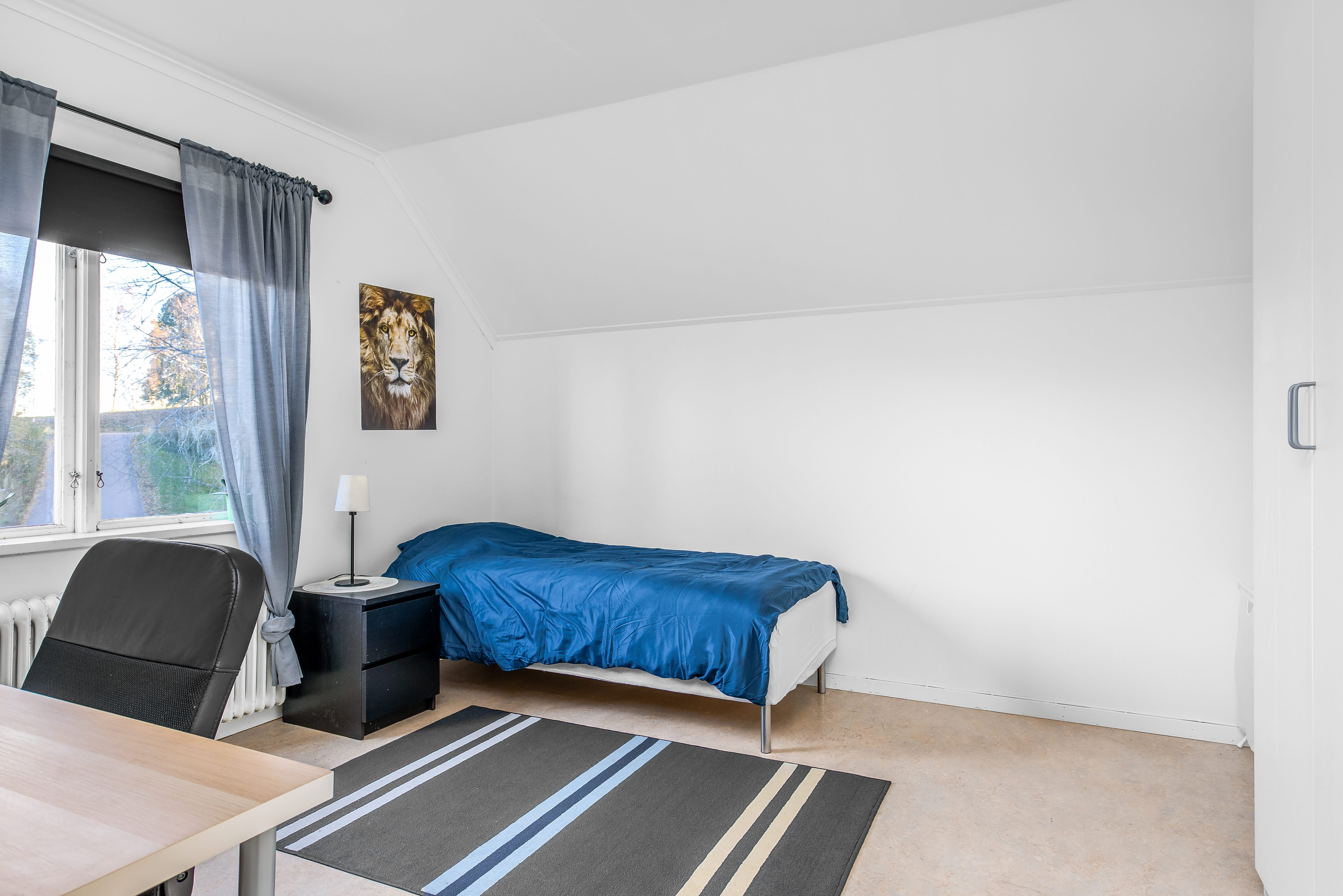 A bedroom with a bed and desk in a room