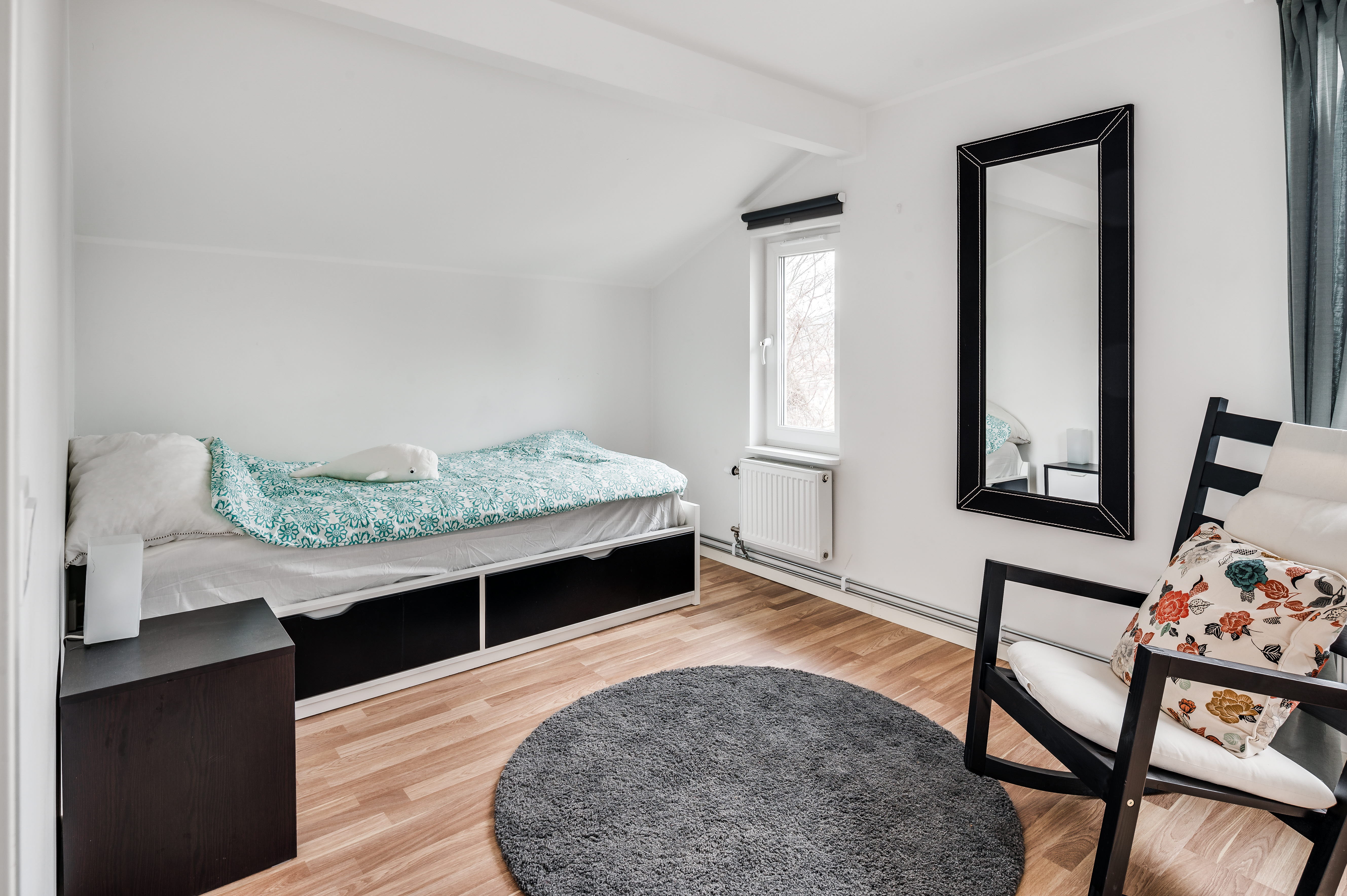 A bedroom with a bed and a chair in a room