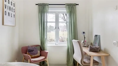 A bedroom with a bed and a chair in a room