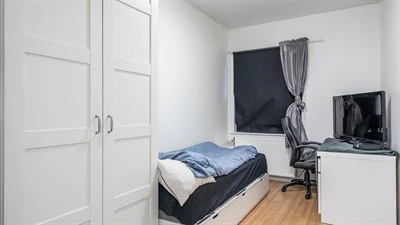 A bedroom with a bed and desk in a small room