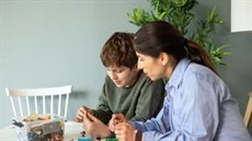 En kvinna och en pojke sitter vid ett bord och leker med lego