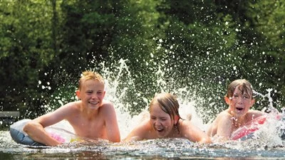 Three children swimming in natural water.