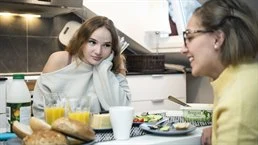 Två kvinnor som sitter vid ett bort och äter frukost