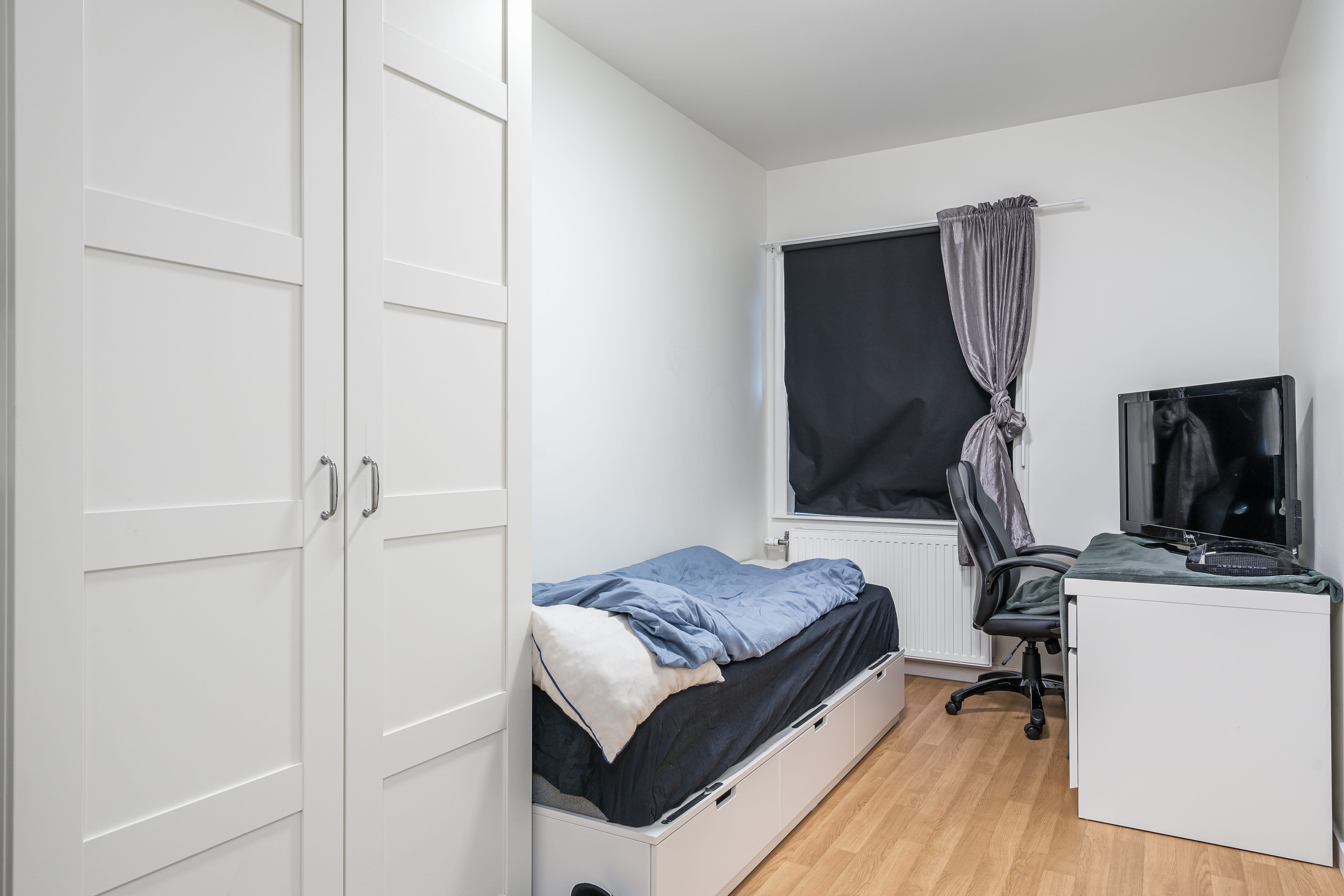 A bedroom with a bed and desk in a small room