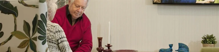 Two elderly people sitting and watching TV