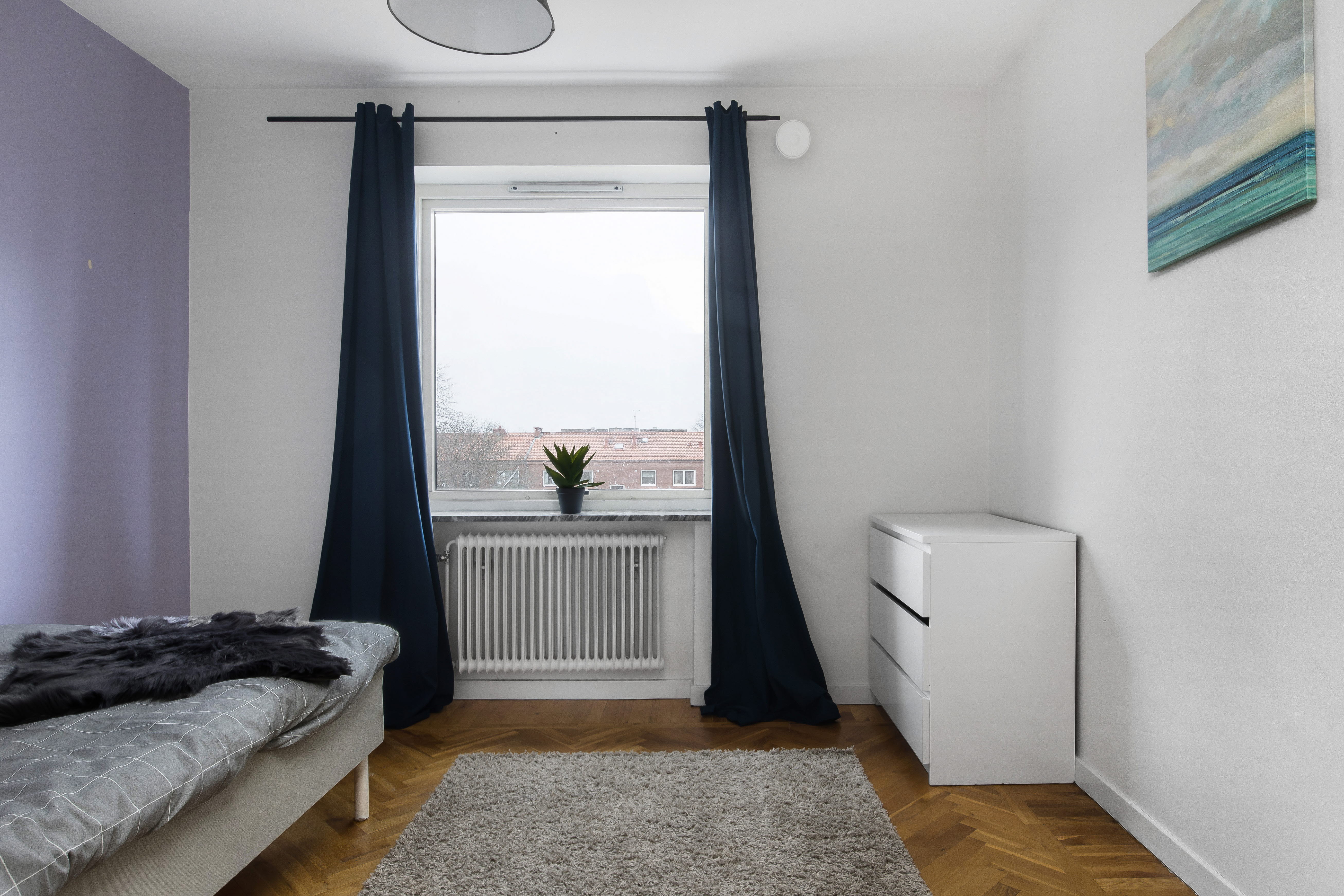 A bedroom with a bed and desk in a room