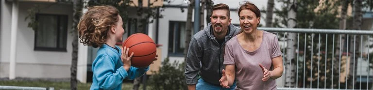 Child playing basketball with two adults
