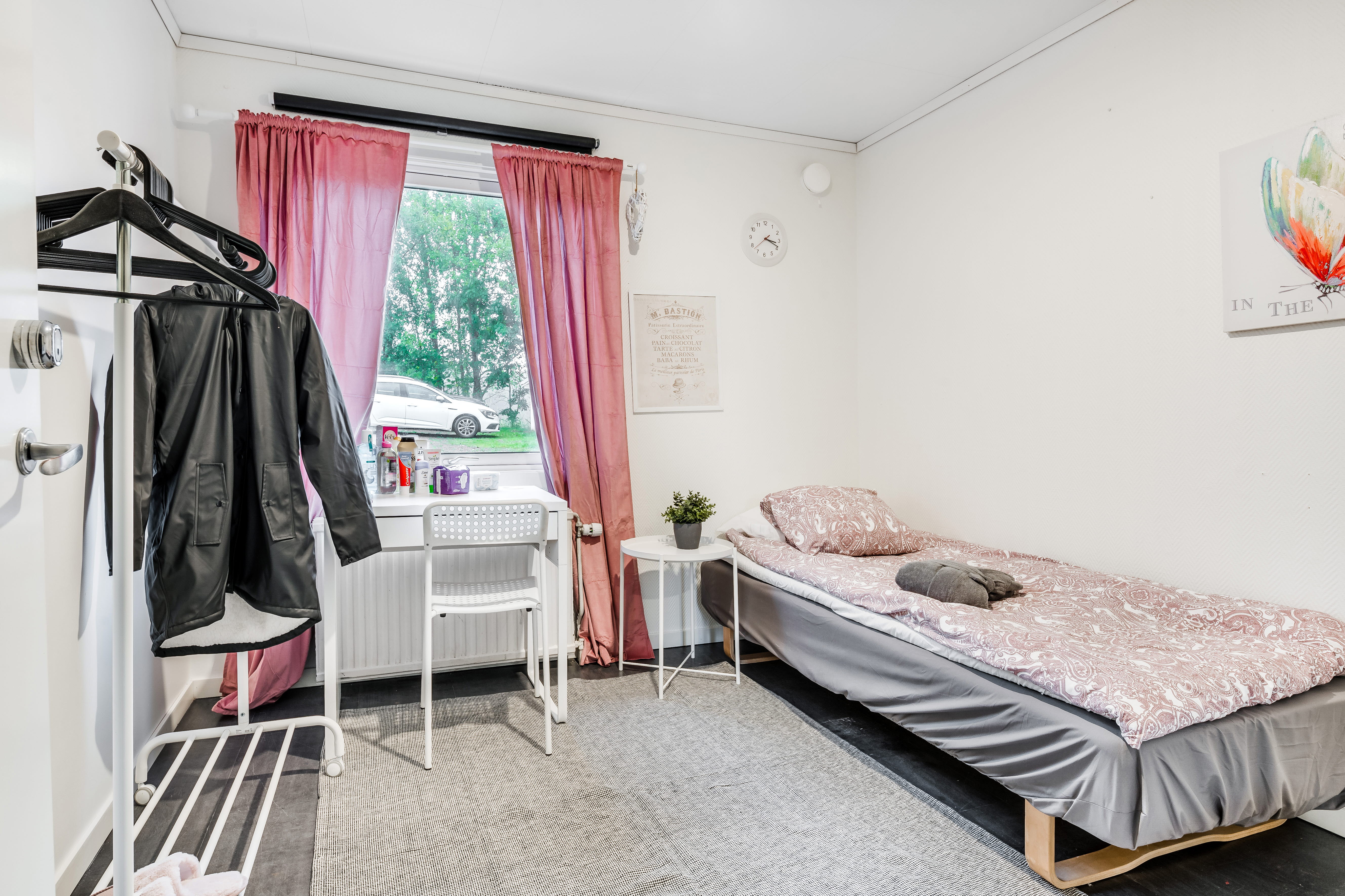 A bedroom with a bed and desk in a small room