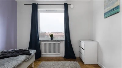 A bedroom with a bed and desk in a room
