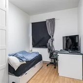 A bedroom with a bed and desk in a small room