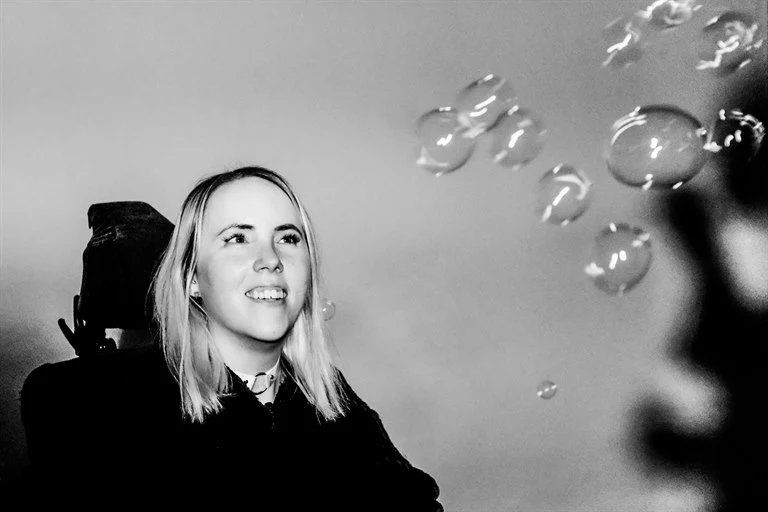 Kvinna sitter i permobil och kollar på bubblor