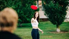 Nuori nainen heittää frisbeetä.
